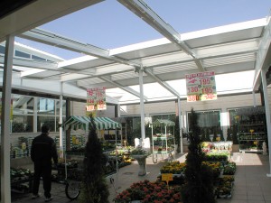 Techo móvil abierto sobre el espacio exterior de una floristería ubicada en un centro comercial.