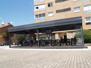 Vista frontal de una terraza de invierno con los paneles exteriores de cristal totalmente replegados.