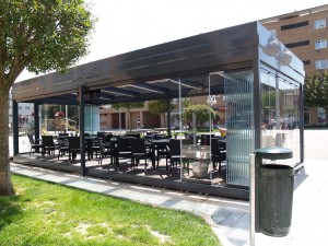 Terraza de un bar de Zizur con paneles deslizantes de cristal sin perfilería que cubren todos los laterales.